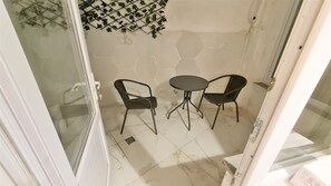 A small, enclosed patio area with a glass door, two wicker chairs, and a round table. - Cozy 1BR Located Near the UNESCO World Heritage Green Masjid in Bursa City (Yıldırım)