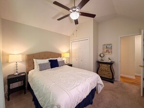 A bedroom with a bed, a nightstand, a dresser, a ceiling fan, and a door. - Near Helen | Dog-Friendly Mountain Retreat + Pool (Sautee Nacoochee)