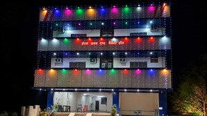A multi-story building with a staircase leading to the entrance, air conditioning units, and a sign with text. - Classic Utsav Inn (Begusarai)