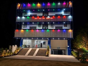 Un edificio de varios pisos con una escalera que conduce a la entrada, unidades de aire acondicionado y un letrero con texto.