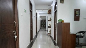 A hotel corridor with wooden doors, a reception desk, and a chair. - Classic Utsav Inn (Begusarai)