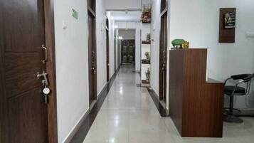 A hotel corridor with wooden doors, a reception desk, and a chair.