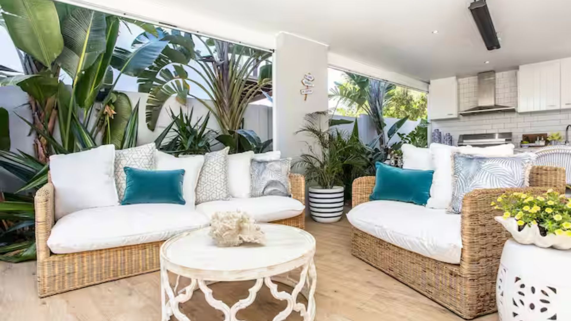 A modern living room with wicker furniture, a white coffee table, and a large potted plant.