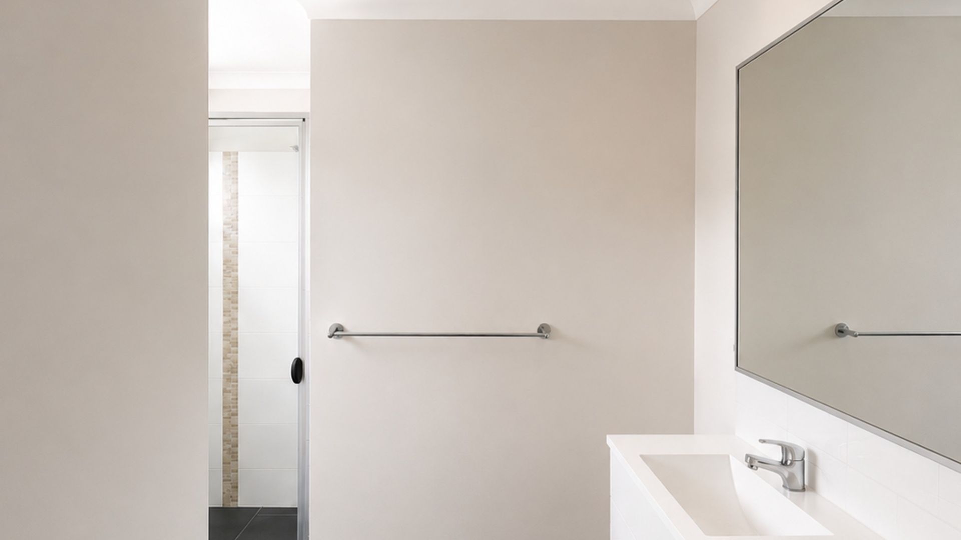 Een moderne badkamer met een witte wasbak, een grote spiegel en een handdoekhouder.