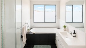 Une salle de bain moderne avec une baignoire, une douche et une grande fenêtre.