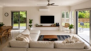 Un salon moderne avec un grand canapé, un téléviseur à écran plat et un ventilateur de plafond.