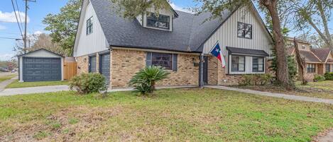 A residential house with a garage, a front yard, and a flag.