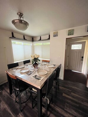 A dining area with a marble table, black chairs, and a vase of flowers.