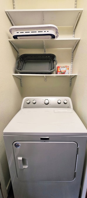 A compact washer and dryer unit with a control panel and a small shelf above it.