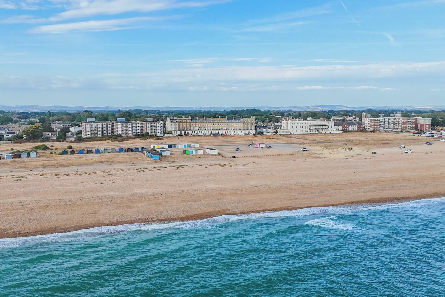Ein Küstenstrand mit Gebäuden im Hintergrund.