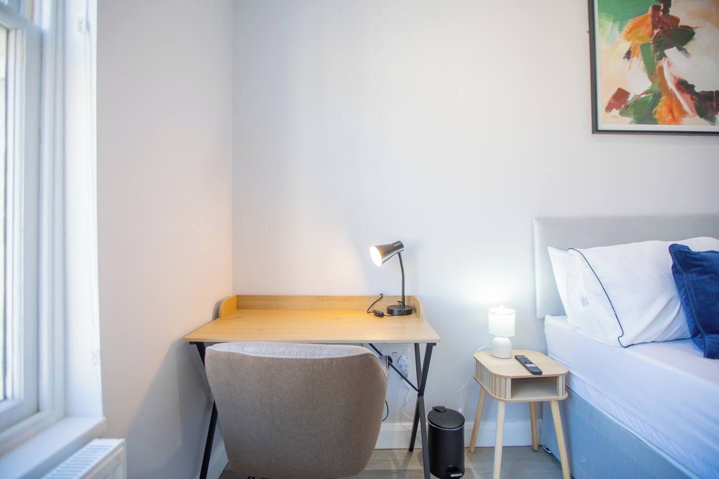 Ein Hotelzimmer mit einem Bett, einem Schreibtisch mit Lampe, einem Sessel und einem kleinen Nachttisch mit Lampe.