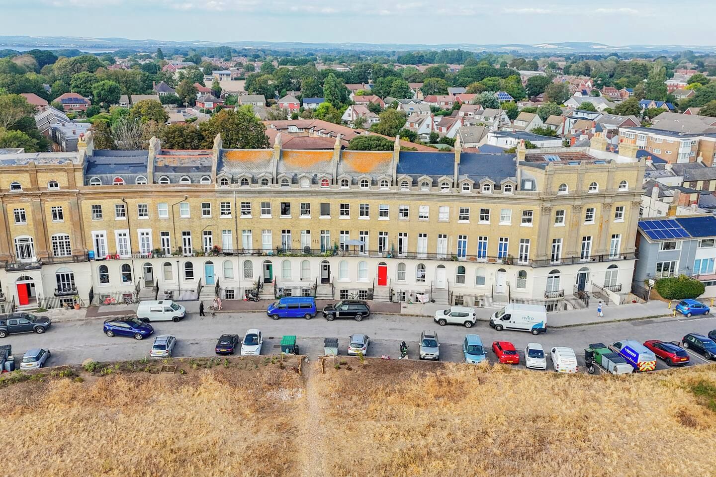 Une rangée de maisons mitoyennes avec un parking devant.