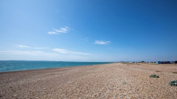 A pebbled beach with a clear sky and distant buildings.
