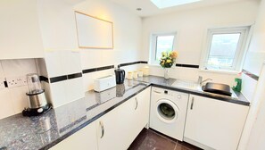 A modern kitchen with a washing machine, a coffee maker, and a toaster. - Temporary Medway Kent Homel Families & Relocation (Chatham)