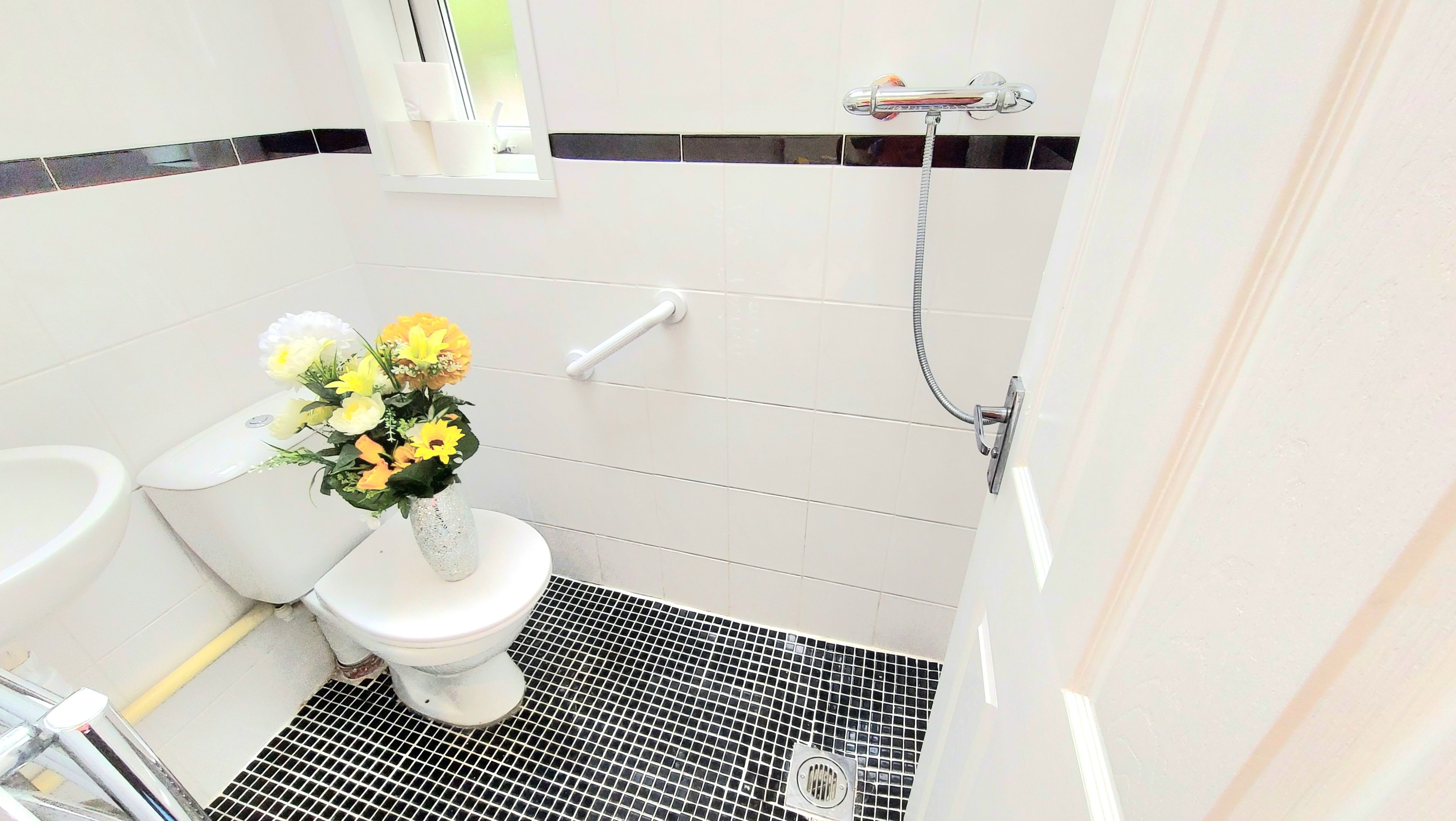 A bathroom with a toilet, a shower, and a sink.