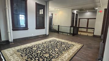 A spacious room with a large patterned rug, wooden flooring, and a skylight.
