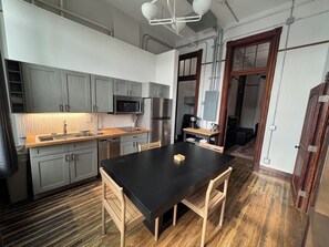 A modern kitchen with grey cabinets, a black countertop, and stainless steel appliances.