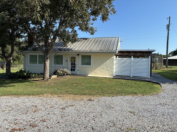 A single-story house with a garage, a small porch, and a gravel driveway.