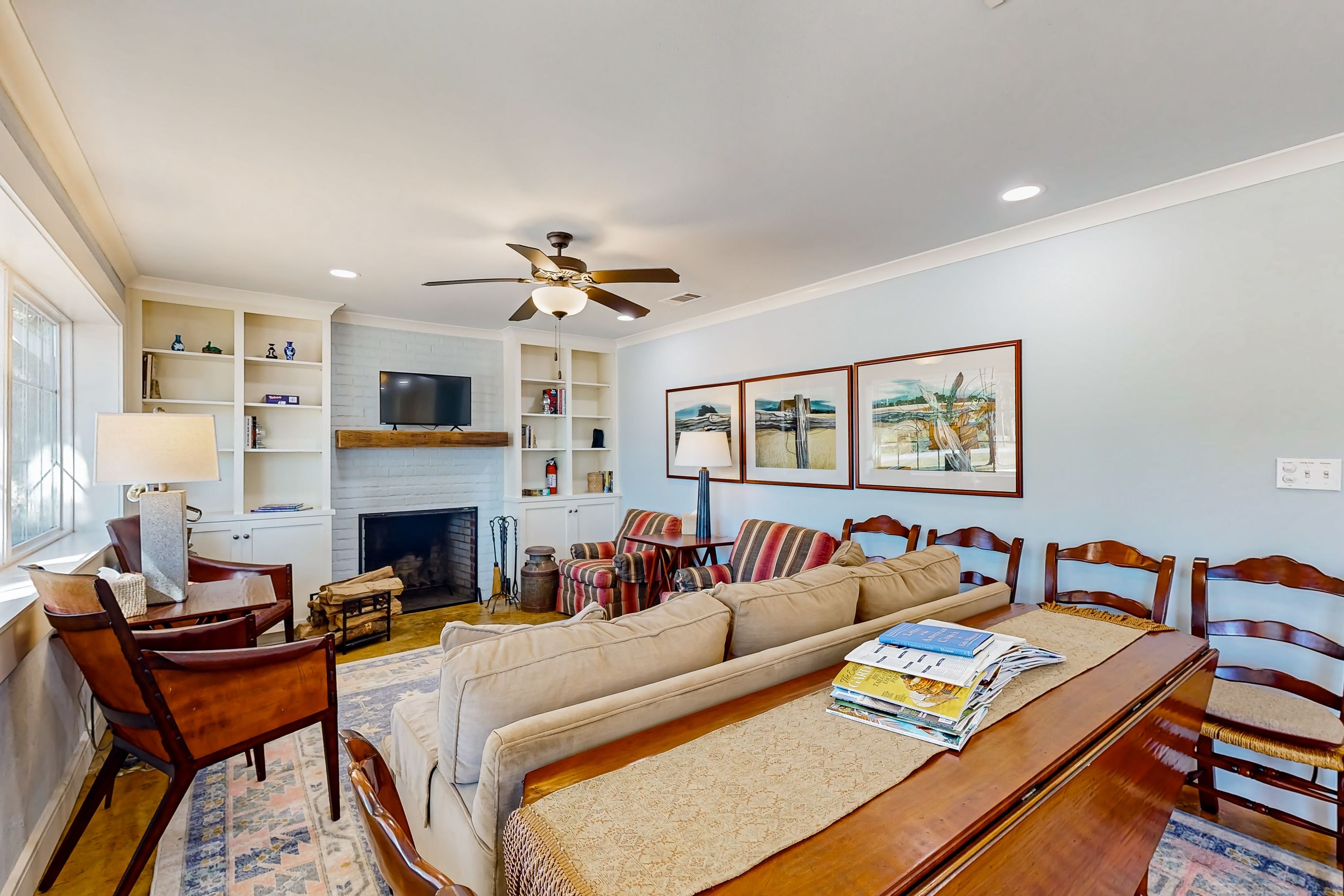 A living room with a sofa, chairs, a fireplace, a television, and shelves with books and decorative items.