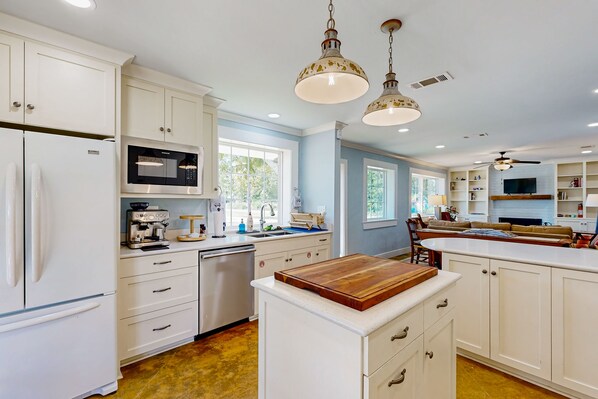 A modern kitchen with white cabinetry, a built-in microwave, and a coffee machine.