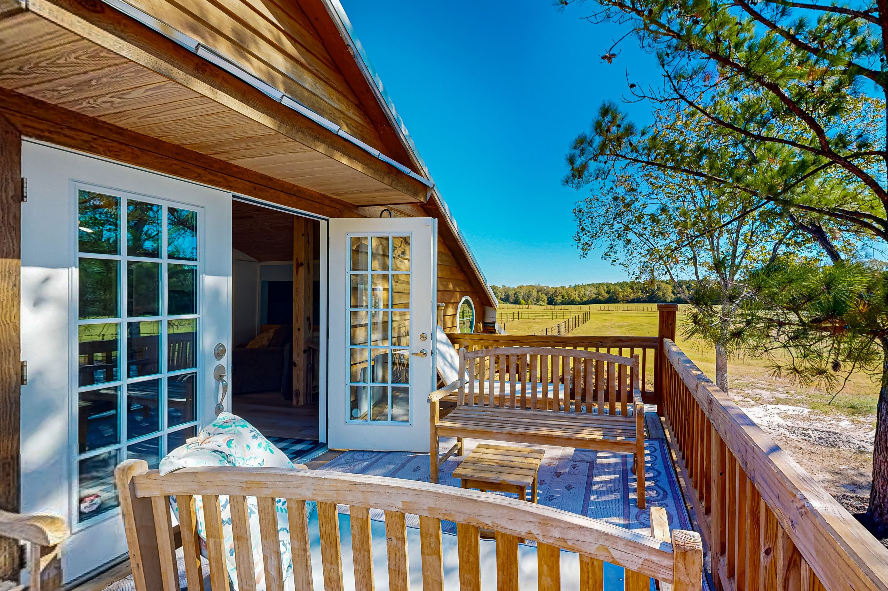 A wooden cabin with a deck, a door leading inside, and a view of the surrounding landscape.