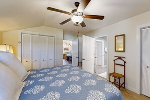 A bedroom with a bed, a ceiling fan, a wardrobe, and a mirror.
