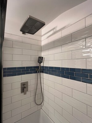 A shower area with white tiles and a blue accent border. - Cozy Log Cabin Retreat (Macon)