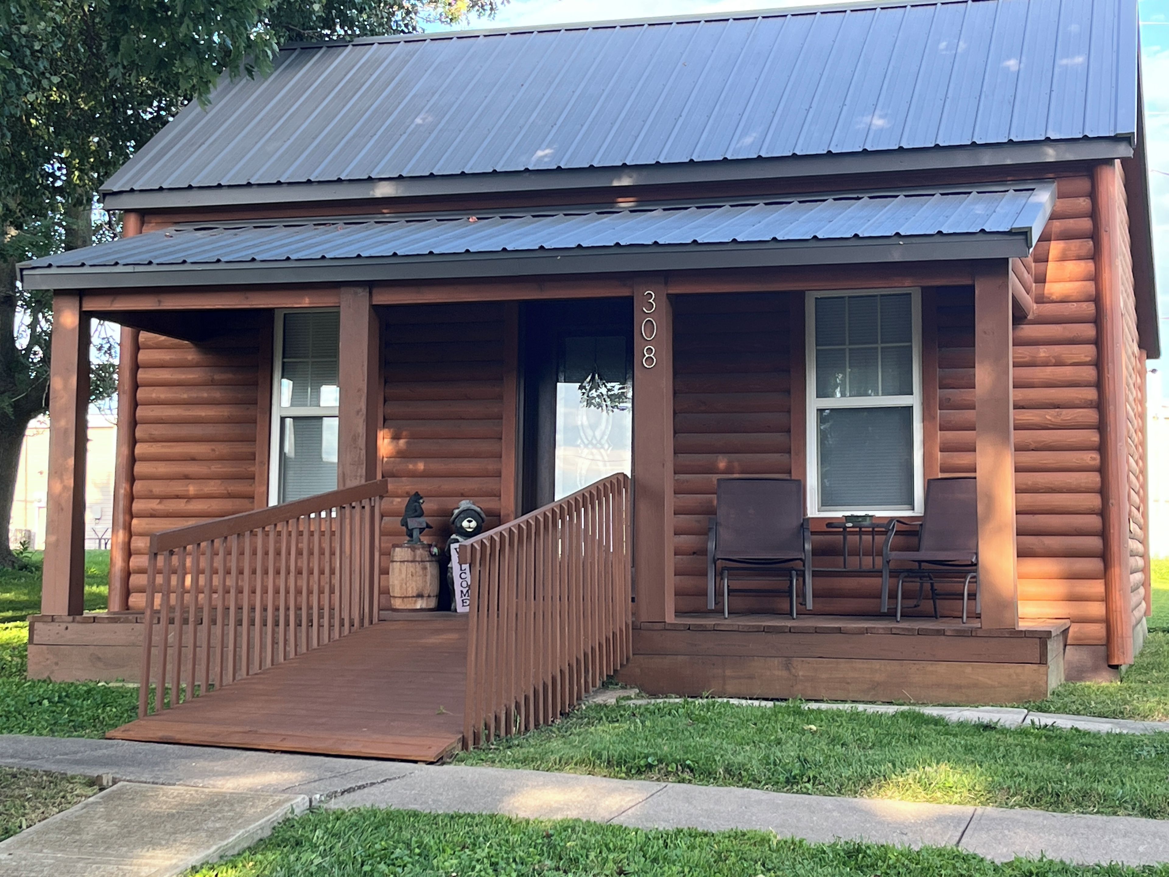 A wooden cabin with a porch, a staircase, and a mailbox.