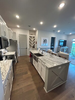 A modern kitchen with a large island, built-in appliances, and a view to the living area. - Grand Junction Football Condo! Walkable to Stadium and golf cart service. (Starkville)