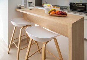 A kitchen with a wooden countertop, two white bar stools, a basket of fruit, and a coffee maker. - Modern and Cozy Two BR Apt with Pool&Free Parking (Fernando de la Mora)