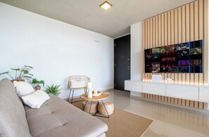 Un salon moderne avec un canapé, une table basse ronde et un téléviseur fixé au mur diffusant du contenu Netflix.