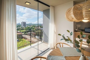 Eine moderne Wohnung mit Balkon, Essbereich und Blick auf die Stadtlandschaft.