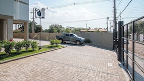 A paved parking area with a pickup truck parked, a fenced area, and a building with a flat roof. - Modern and Cozy Two BR Apt with Pool&Free Parking (Fernando de la Mora)
