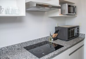 Eine moderne Küche mit integriertem Induktionskochfeld, einer Mikrowelle und einem Messerblock auf der Arbeitsplatte.