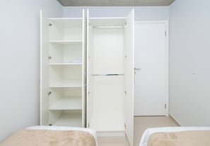 Ein Schlafzimmer mit einem weißen Kleiderschrank, zwei Betten und einer Tür.