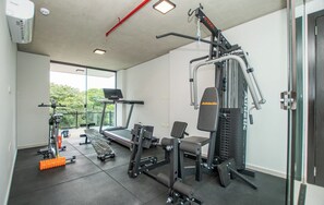 A gym with a treadmill, weight machines, and a bench. - Asunción 2BR | Pool, Gym, Balcony & Parking (Asunción)