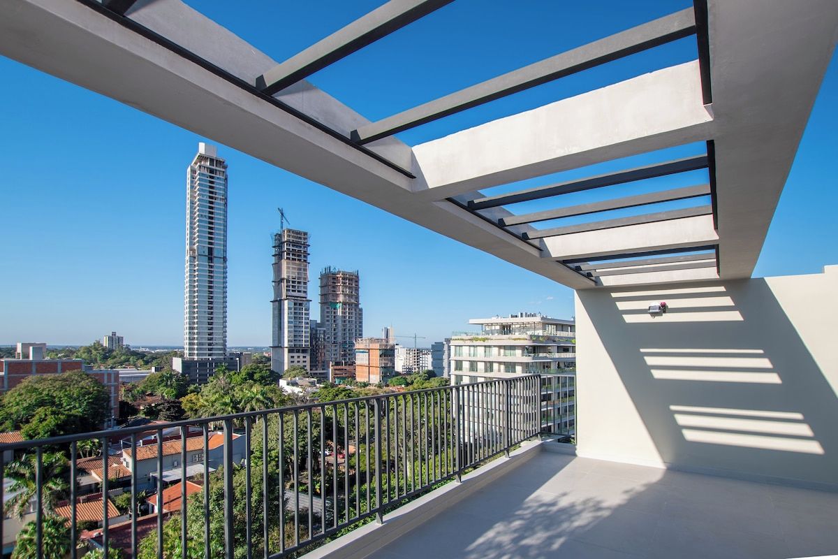 A balcony with a view of a cityscape, including high-rise buildings and construction sites.