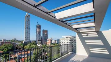 A balcony with a view of a cityscape, including high-rise buildings and construction sites.