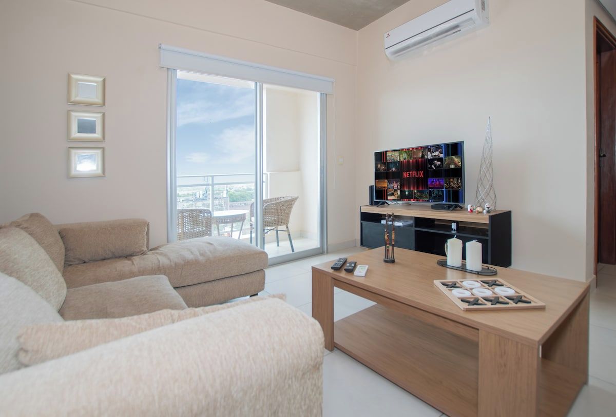 Een moderne woonkamer met een bank, een salontafel, een flatscreen televisie en een balkon met uitzicht.