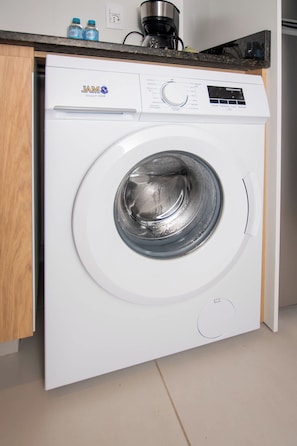 Eine Waschmaschine mit Frontlader und digitaler Bedienoberfläche, gelegen in einer Küche mit Holzausbau und Arbeitsplatte.