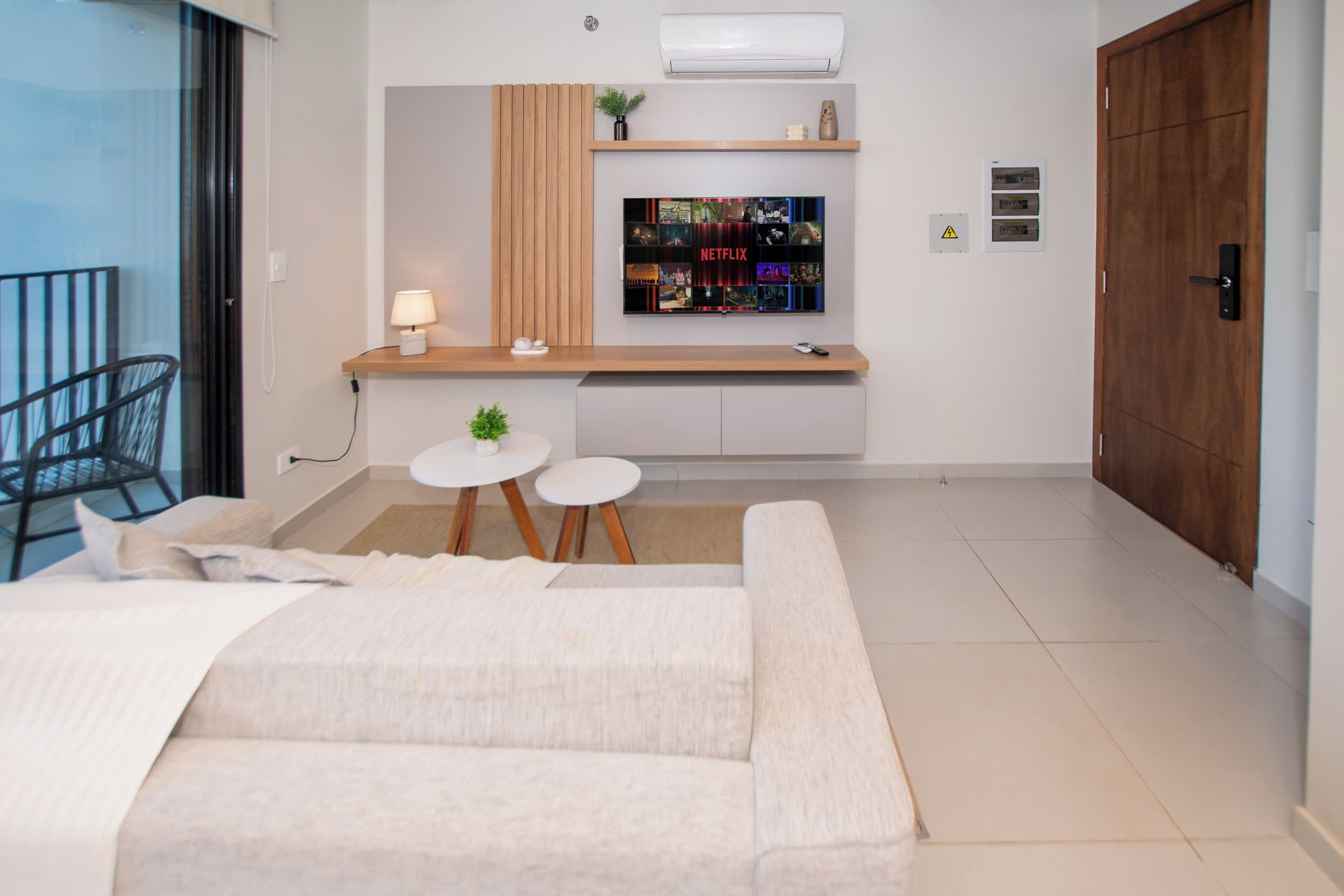A modern living room with a sofa, a small round table, and a TV mounted on the wall.