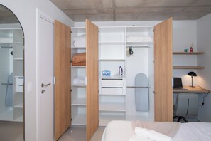 Ein Schlafzimmer mit einem Bett, einem Schreibtisch mit einem Laptop und einem geöffneten Kleiderschrank.