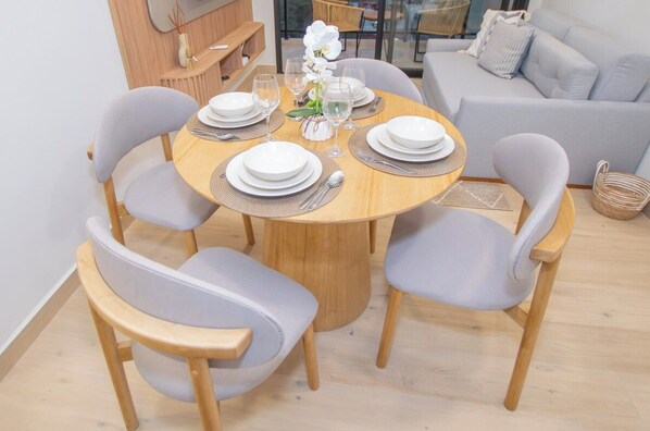 Een eetgedeelte met een ronde houten tafel voor vier personen, omringd door grijs gestoffeerde stoelen.