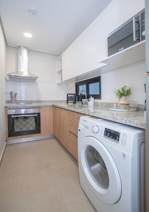 Een moderne keuken met een inbouwoven, magnetron en wasmachine.