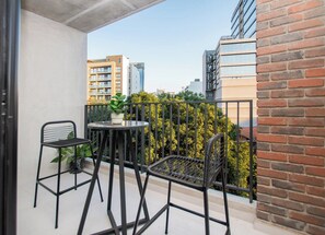 Ein Balkon mit zwei Stühlen, einem kleinen Tisch, einem Metallgeländer und einem Blumentopf.
