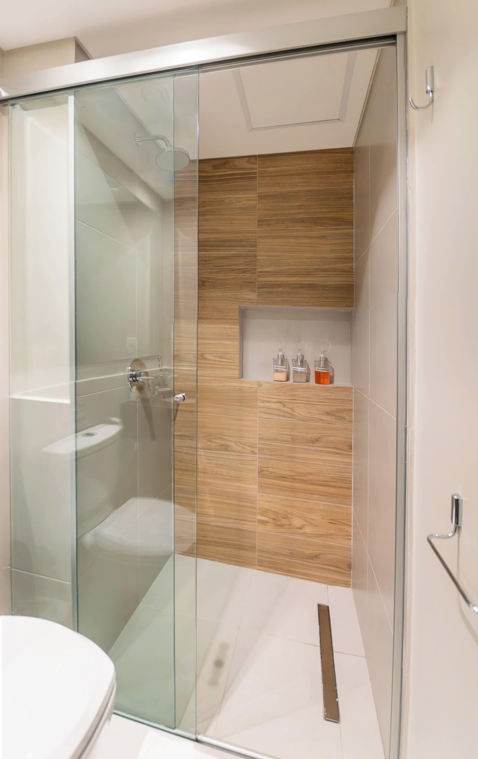 Un baño moderno con cabina de ducha de vidrio, tocador de madera y inodoro.