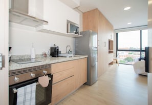 A modern kitchen with a built-in oven, a microwave, and a refrigerator. - Modern Studio with Rooftop Pool, Gym & 200 Mbps WiFi (Asunción)