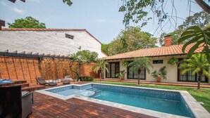 A swimming pool with a wooden deck, lounge chairs, and potted plants. - 4BR Home | Private Pool, Jacuzzi & BBQ (San Bernardino)