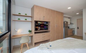 Ein modernes Schlafzimmer mit einem Bett, einem Schreibtisch, einem Stuhl, einem Kleiderschrank und einem Regal mit Büchern und Dekoration.