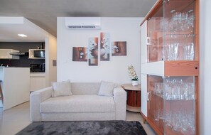 Ein modernes Wohnzimmer mit einer Couch, einer Glasvitrine mit Glaswaren und Wandbildern.